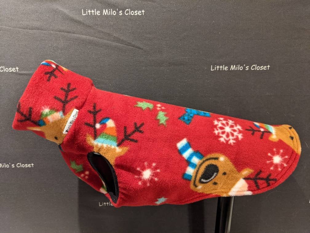 Red Christmas fleece vest with reindeer in winter hats and snowflakes on a display stand