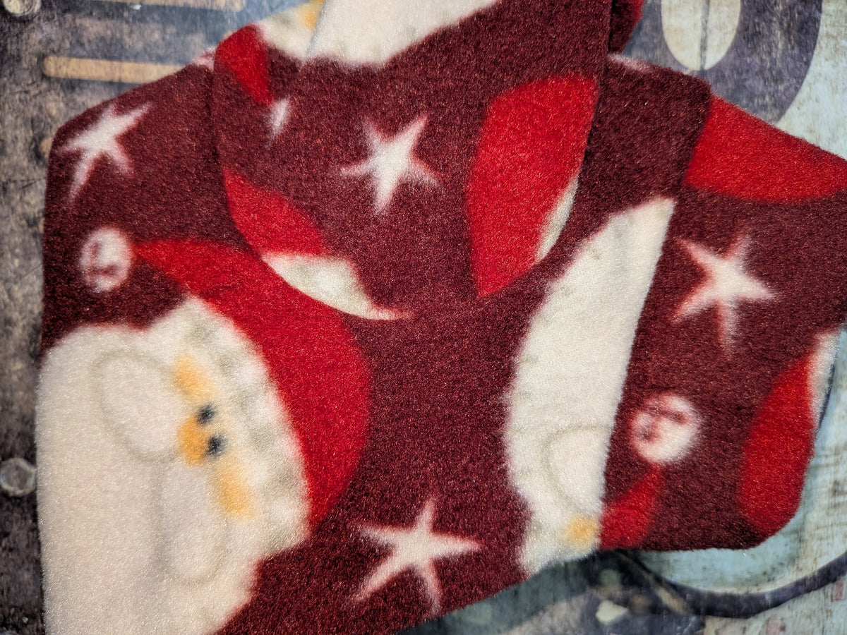 Close-up of burgundy Tossed Santa Heads fleece jammies with Santa faces and white stars