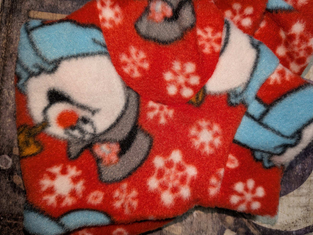 Close-up of red Christmas fleece jammies with snowmen in blue scarves and white snowflakes
