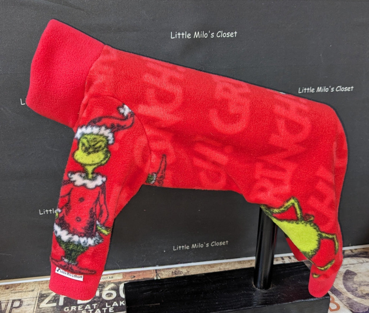 Red Grinch plush fleece jammies for Italian Greyhounds with tonal GRINCH lettering and the green character, on a stand