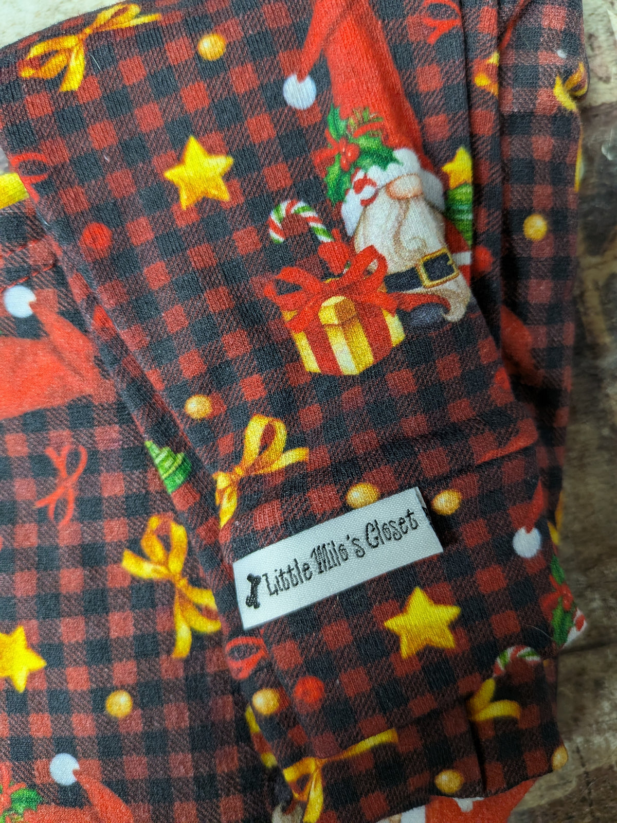 Checked Santas two legged top in red and black buffalo check with Santa, presents, stars and bows