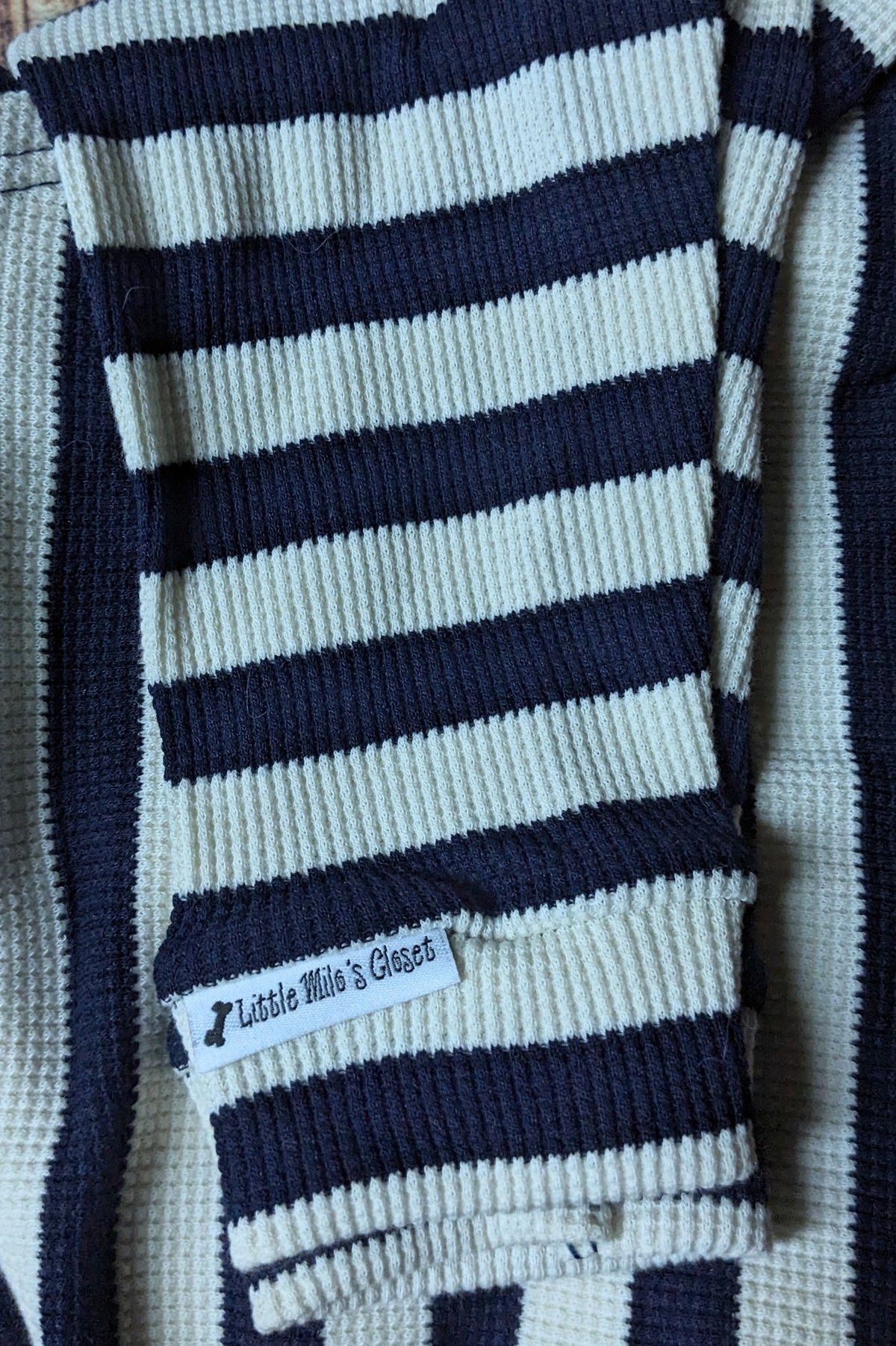 Navy and cream striped knit Italian Greyhound sweater, folded close-up of the sleeve and label