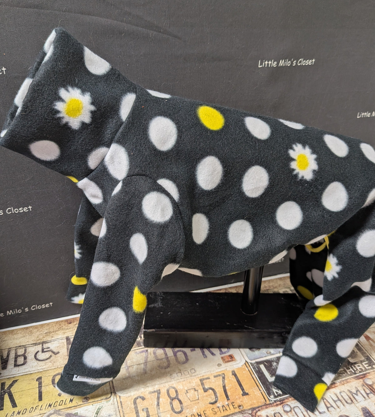 Black fleece bodysuit with white polka dots and daisies, side view on an Italian Greyhound dog form