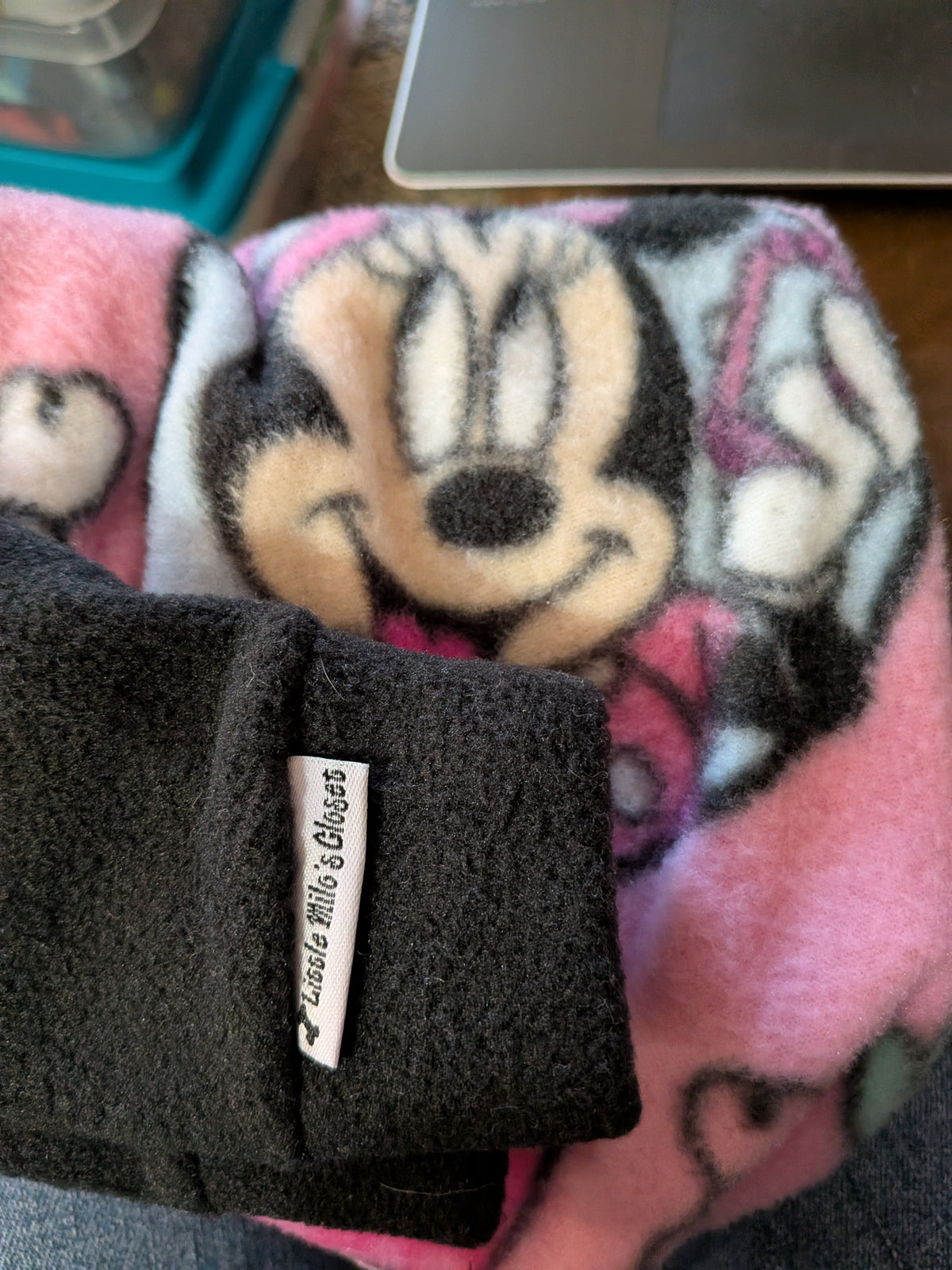 Folded pink Minnie and friends fleece Italian Greyhound bodysuit with a black cuff and brand label