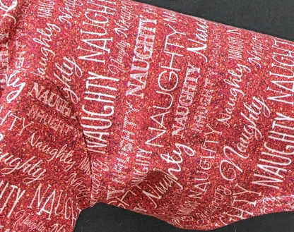 Close-up of red Naughty two legged Christmas top with sparkly script and block lettering