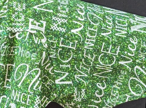 Close-up of green Nice two legged Christmas top with sparkly script and block lettering