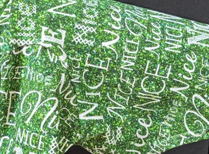 Close-up of green Nice two legged Christmas top with sparkly script and block lettering