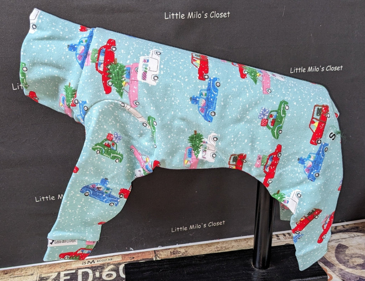 Light blue Christmas Cars bodysuit with red trucks carrying trees, shown on an Italian Greyhound display form