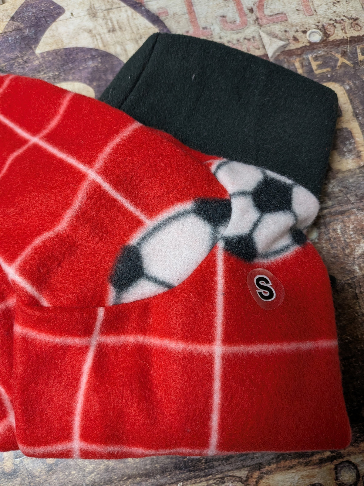 Folded red windowpane check plush fleece bodysuit with soccer ball print, black collar and a snap
