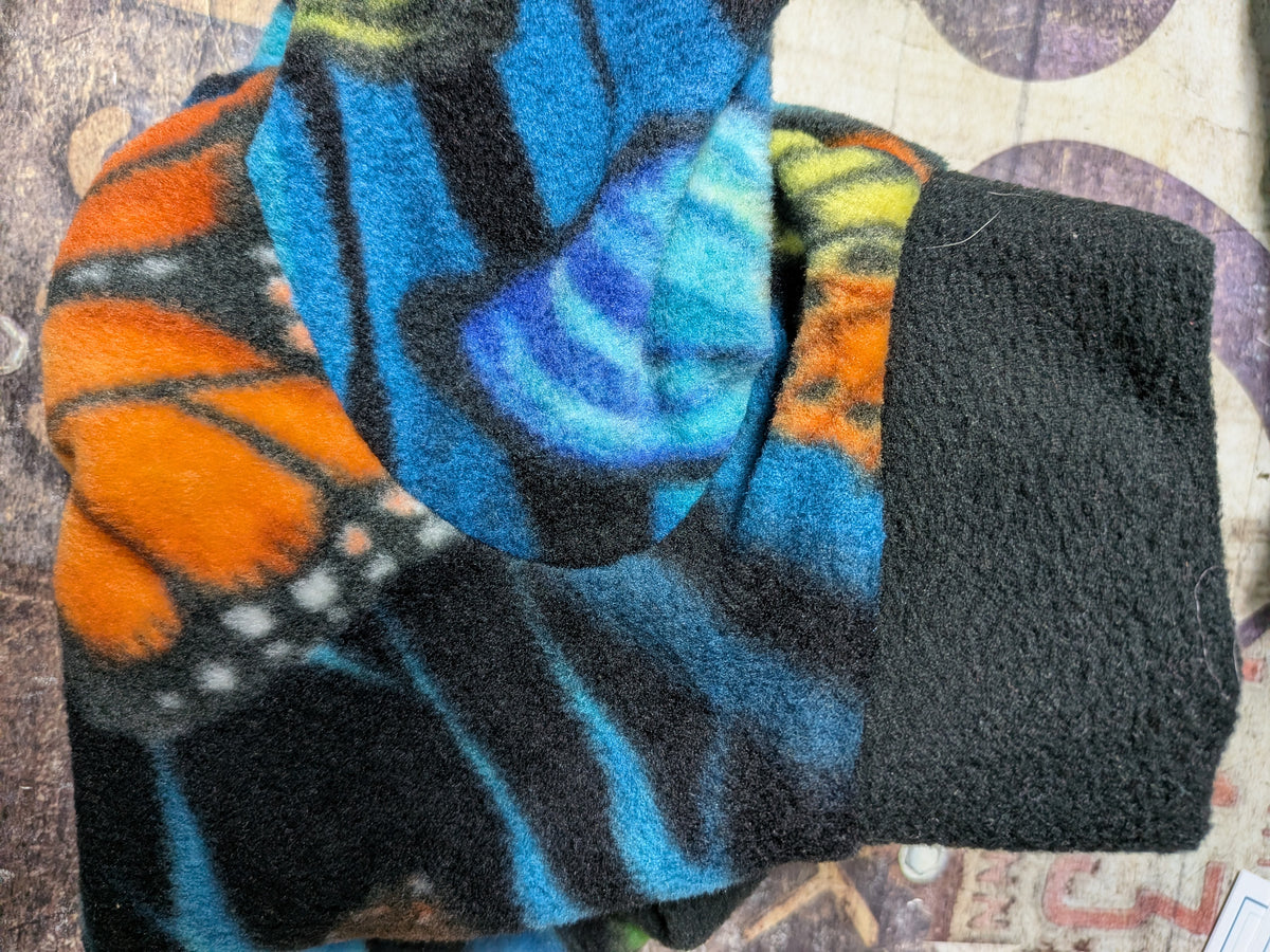 Folded black plush fleece bodysuit with orange monarch and blue butterflies and a solid black cuff