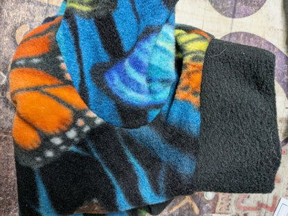 Folded black plush fleece bodysuit with orange monarch and blue butterflies and a solid black cuff