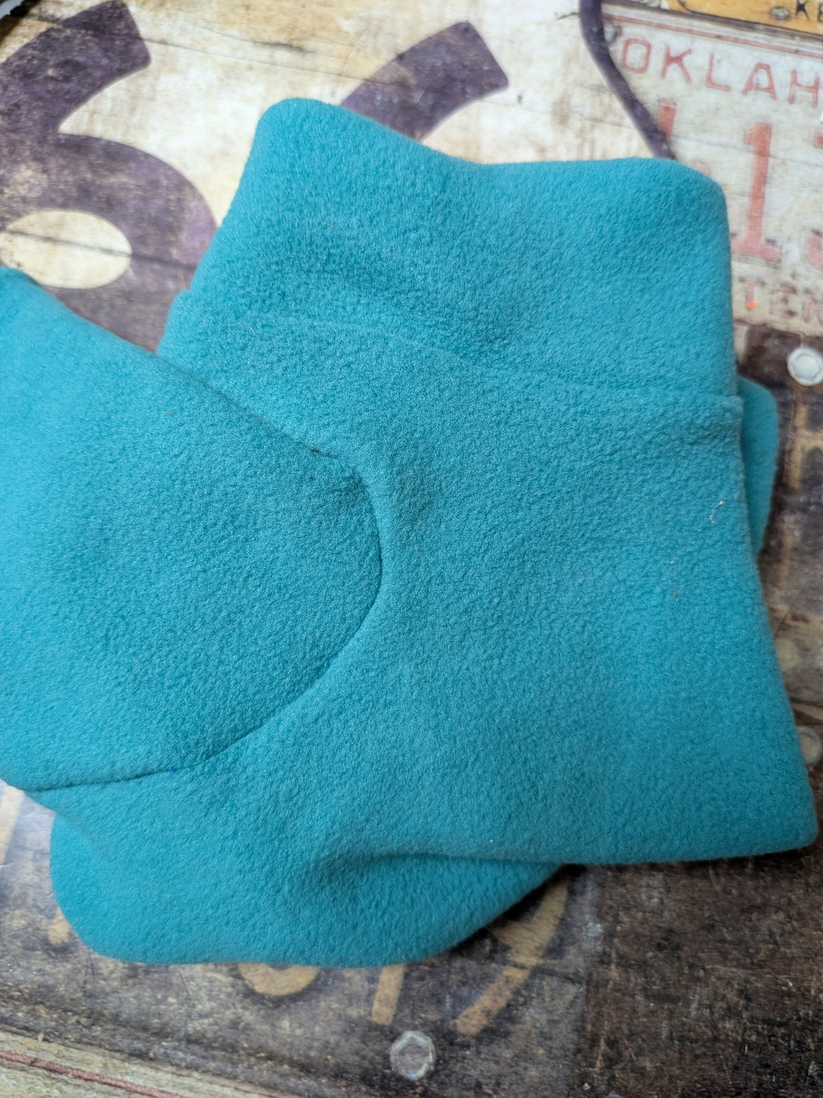 Folded solid teal plush fleece bodysuit for an extra small Italian Greyhound