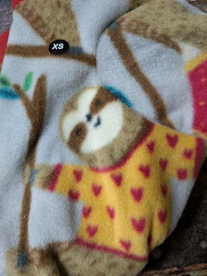 Close-up of a grey plush fleece bodysuit with a sloth in a yellow heart sweater and an XS size tag