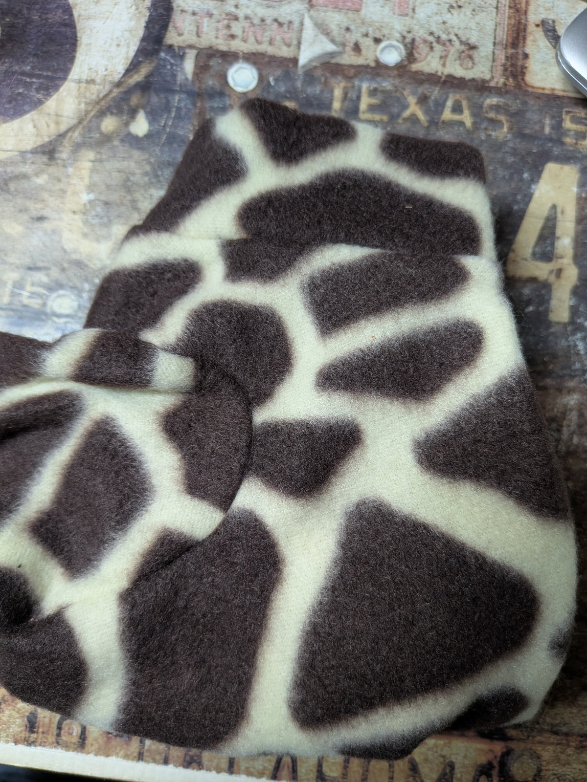 Folded brown and cream giraffe print plush fleece bodysuit for an extra small Italian Greyhound