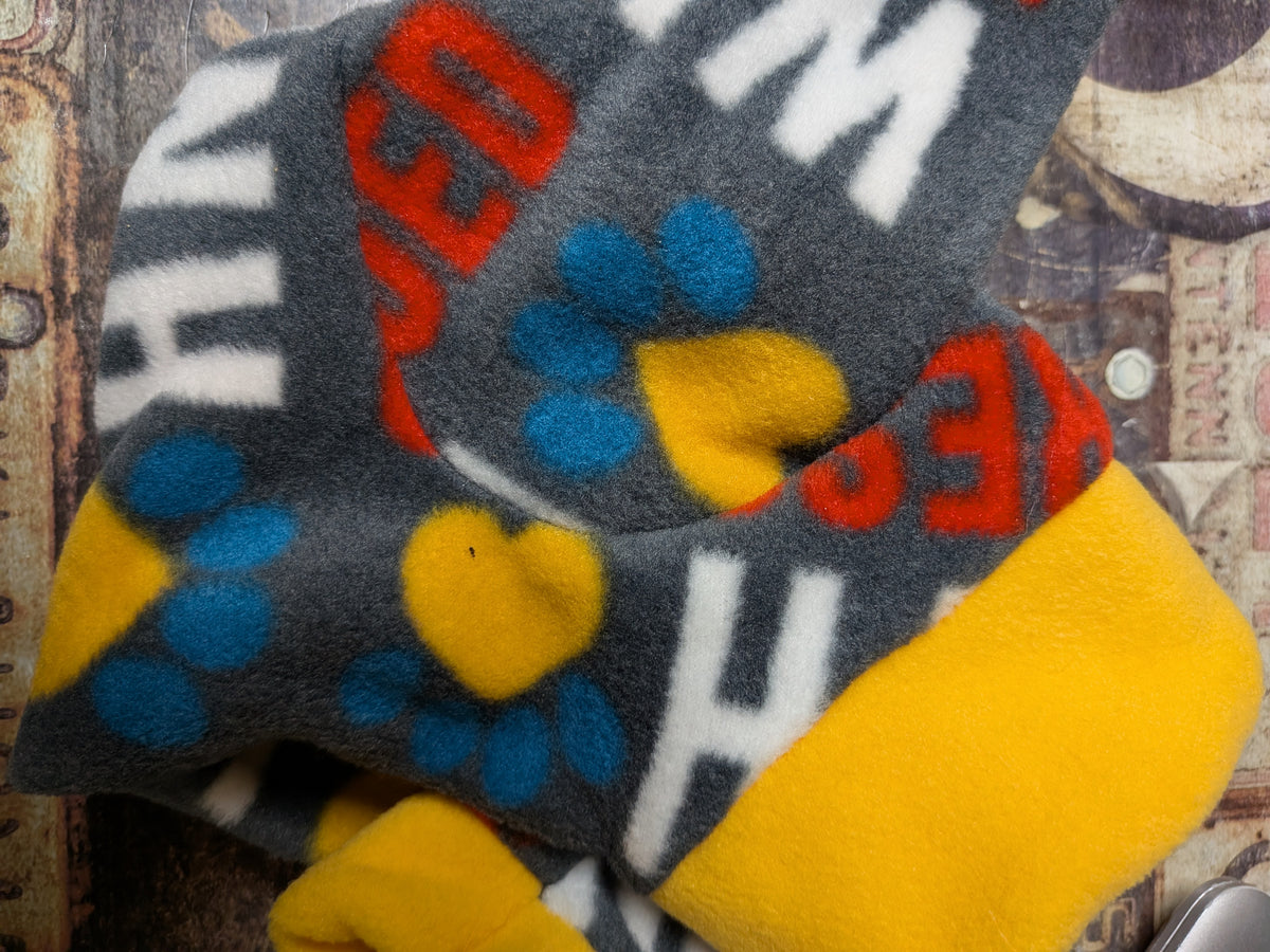Folded charcoal plush fleece bodysuit with blue paw prints, yellow hearts, word print and a yellow cuff