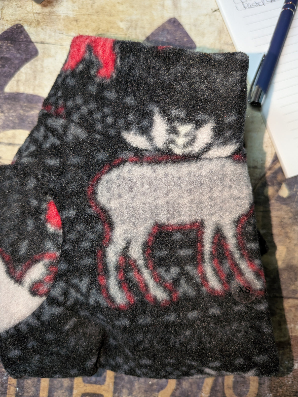 Close-up of charcoal Italian Greyhound fleece jammies with a grey and white reindeer print and XS tag