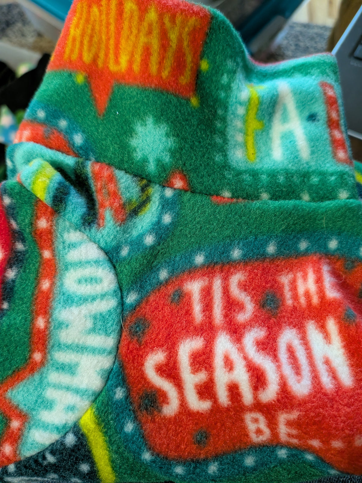Close-up of green fleece jammies with red Tis the Season and holiday word bubbles