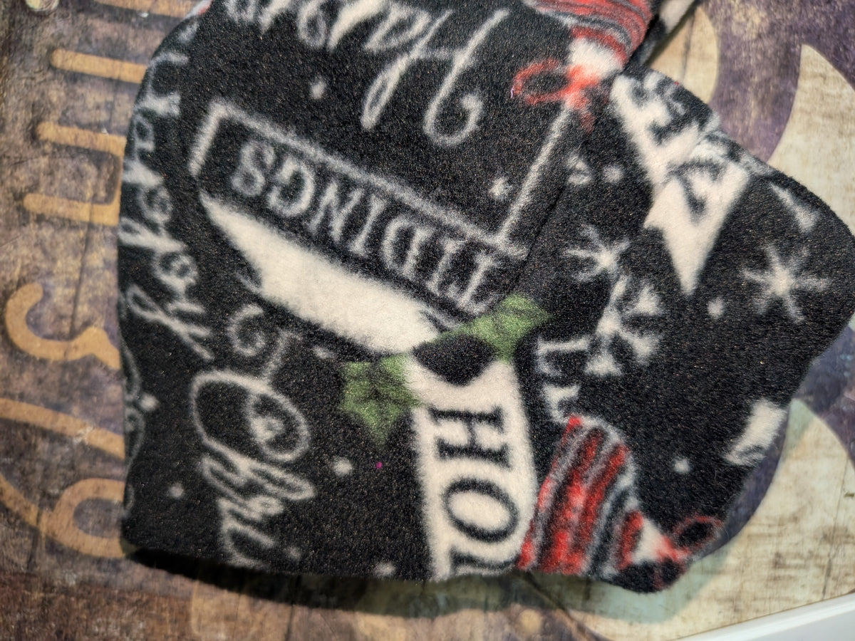 Close-up of black Christmas fleece jammies with white holiday script words and holly