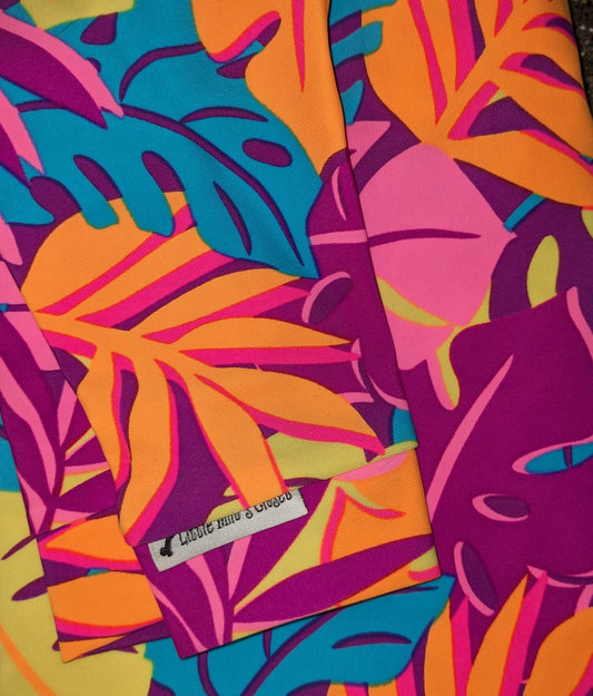 Long sleeved UV top in Neon Jungle print, orange, pink and teal leaves on purple, folded flat