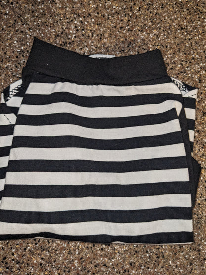 Black and white striped upcycled dog shirt with a black neckband, folded flat lay on a speckled counter