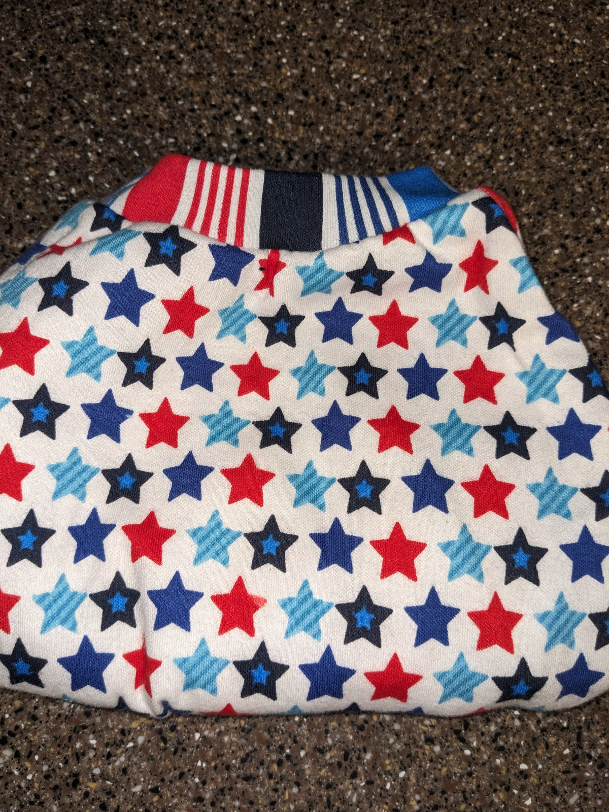 Stars and stripes upcycled dog shirt with red and blue stars on white and a striped neckband, flat lay