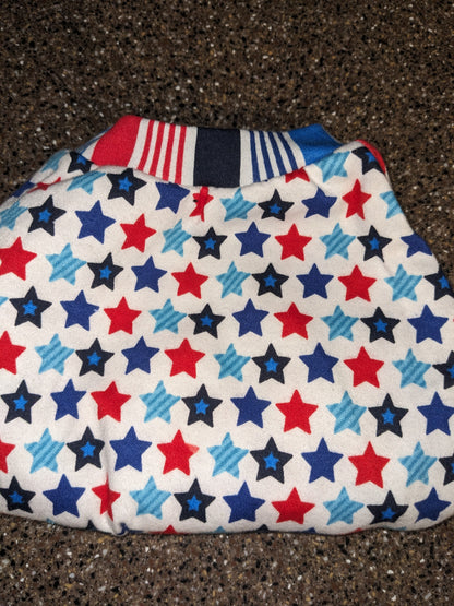 Stars and stripes upcycled dog shirt with red and blue stars on white and a striped neckband, flat lay