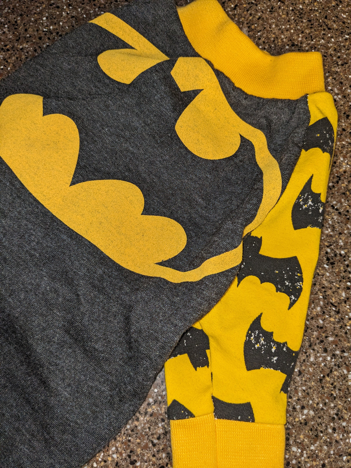Upcycled bat logo dog shirt in charcoal grey with a big yellow bat emblem and yellow bat print sleeves, flat lay