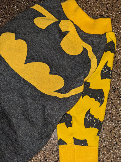 Upcycled bat logo dog shirt in charcoal grey with a big yellow bat emblem and yellow bat print sleeves, flat lay